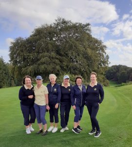 6 woming standing on a golf course wearing navy & lemon